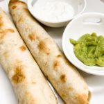 Plate with 2 taquitos, guacamole, and sour cream