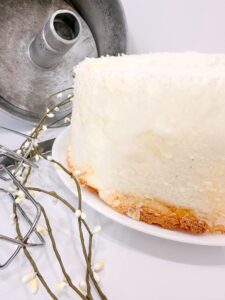 Baked Angel Food Cake on Plate With Pan in the Background.